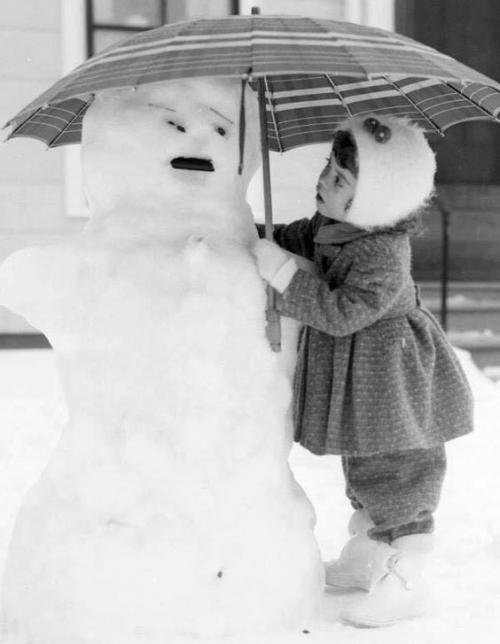 Description de l’image : petite fille protégeant bonhomme de neige d'un parapluie